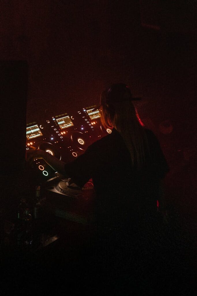 pexels-photo-16981562 A DJ mixes tracks in a dimly lit nightclub with colorful lights and advanced equipment.