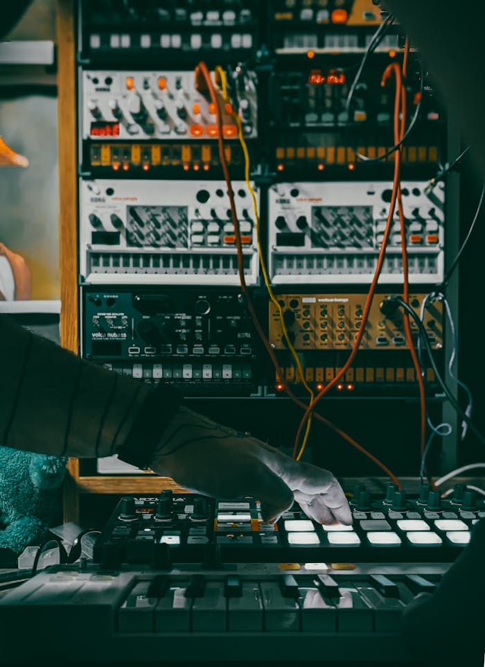 pexels-photo-27007091 Musician using a synthesizer and controllers in a studio with electronic equipment.