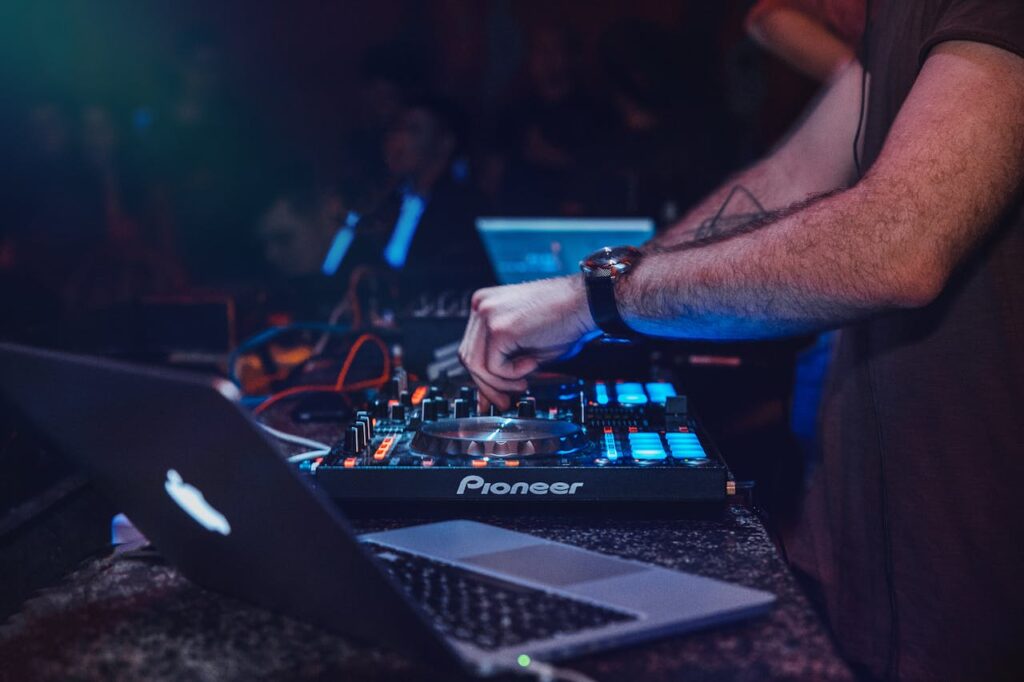 pexels-photo-844928 DJ performing with mixer in a vibrant nightclub setting. Perfect for entertainment and technology themes.